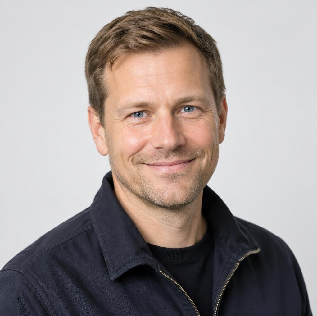 Portrait of a smiling man with short hair in a dark jacket